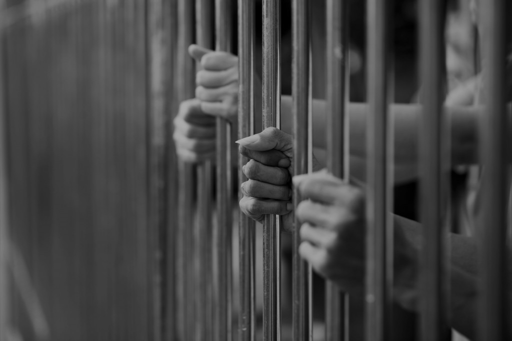 Hands gripping bars of a cell
